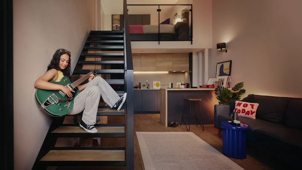 Student relaxing with a guitar in a duplex Vita Student studio